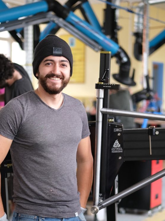 Félix Sanchez, souriant, dans un atelier de fabrication de cadres de vélo.